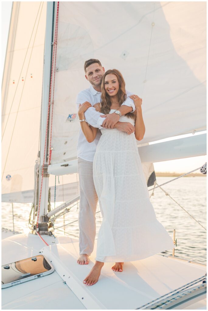 man wrapping his arms around his fiance during engagement session in Carolina Beach