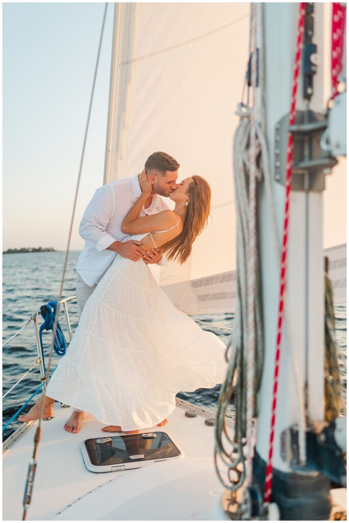 fiance dipping back his fiancee on a sailboat during gulden hour in NC