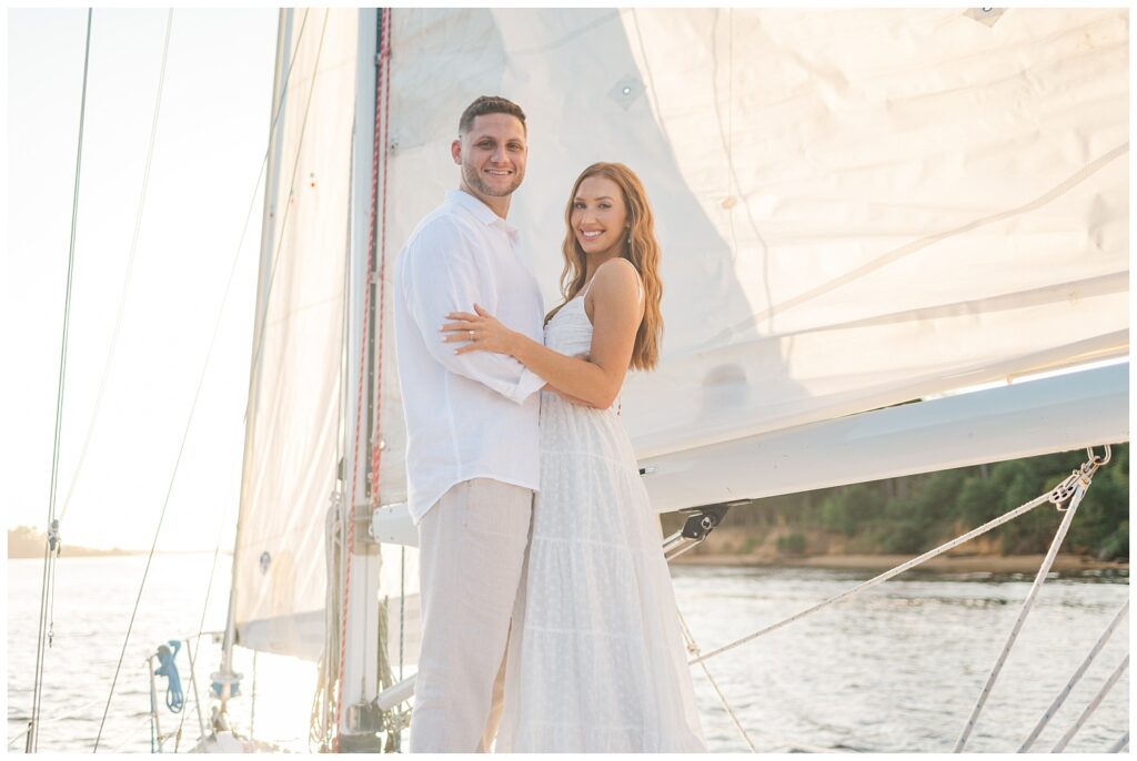 couple standing on a boat with the sunset behind them at Carolina Beach engagement