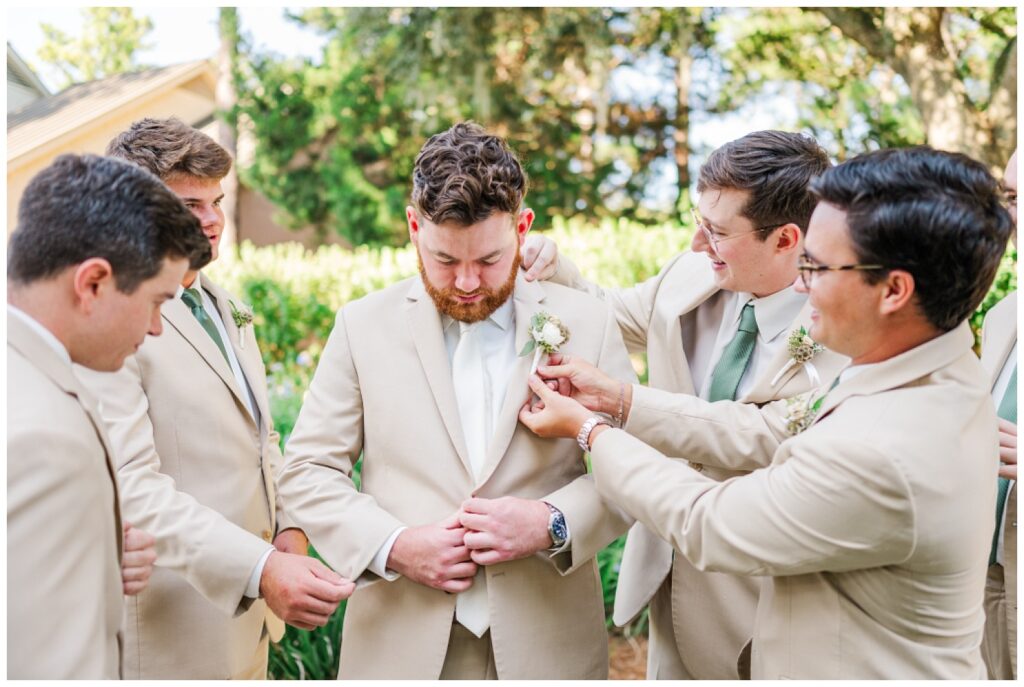 groomsmen adjusting the groom's boutonniere and suit before the wedding