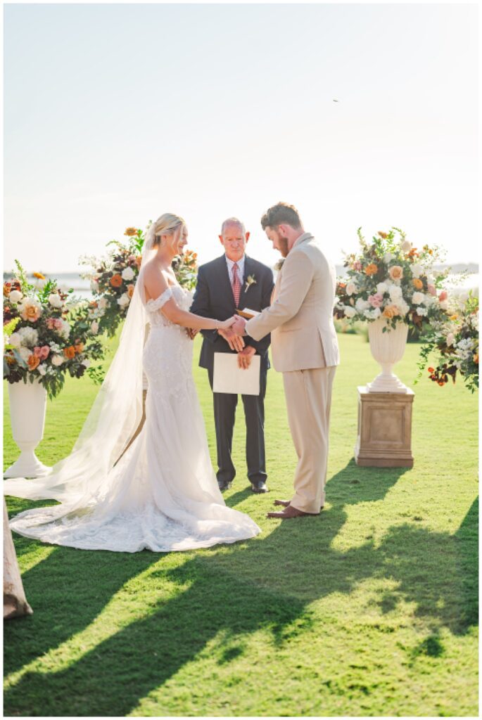 bride and groom hold hands and the groom finishes reading his vows 