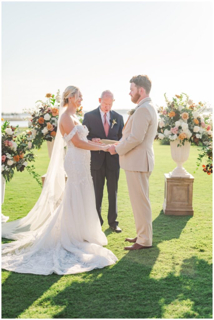 wedding couple holding hands during ceremony outside on golf course at Sea Pines Resort