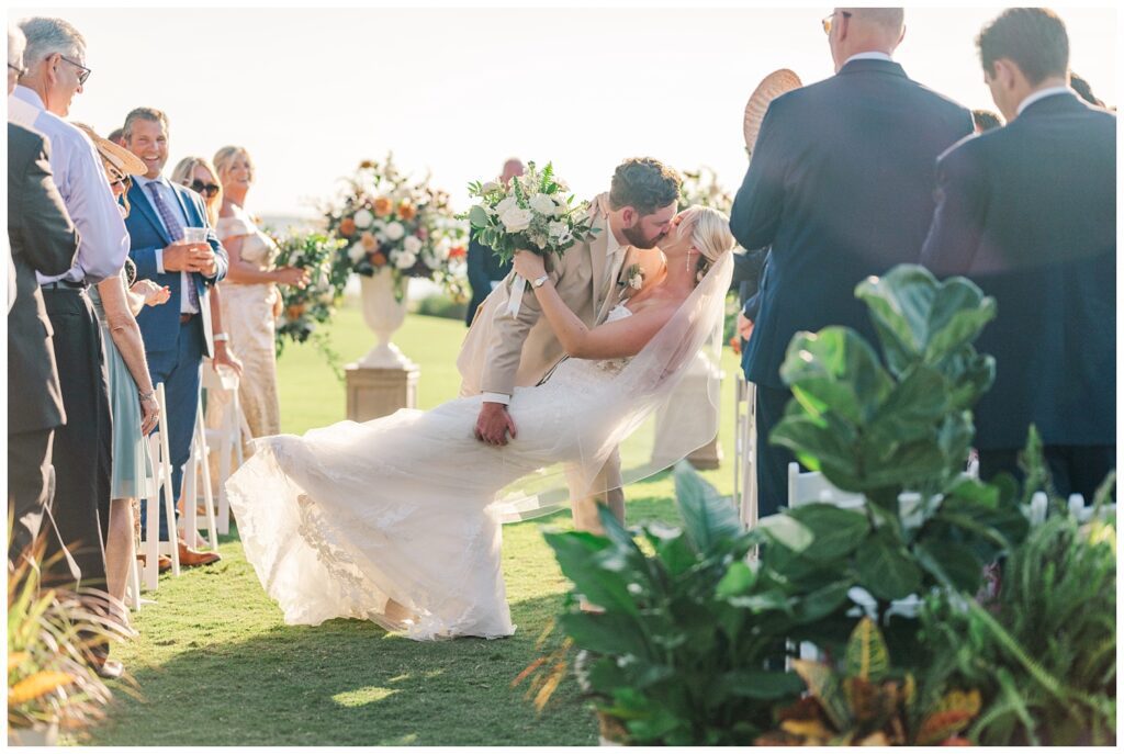 groom dips bride back for a kiss as they walk back down the aisle 