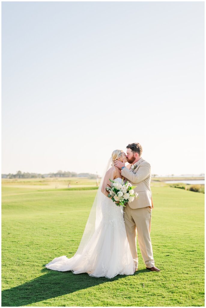 groom and bride kiss on the golf course after outdoor ceremony in Hilton Head