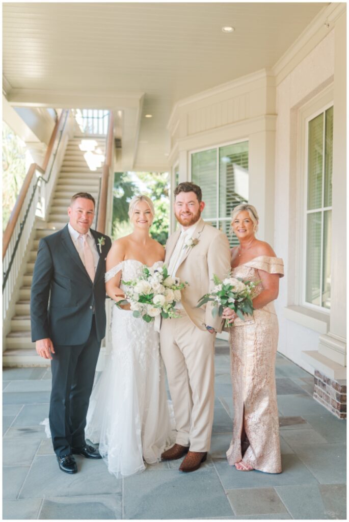 bride and groom posing with bride's parents under the balcony at Sea Pines Resort wedding venue