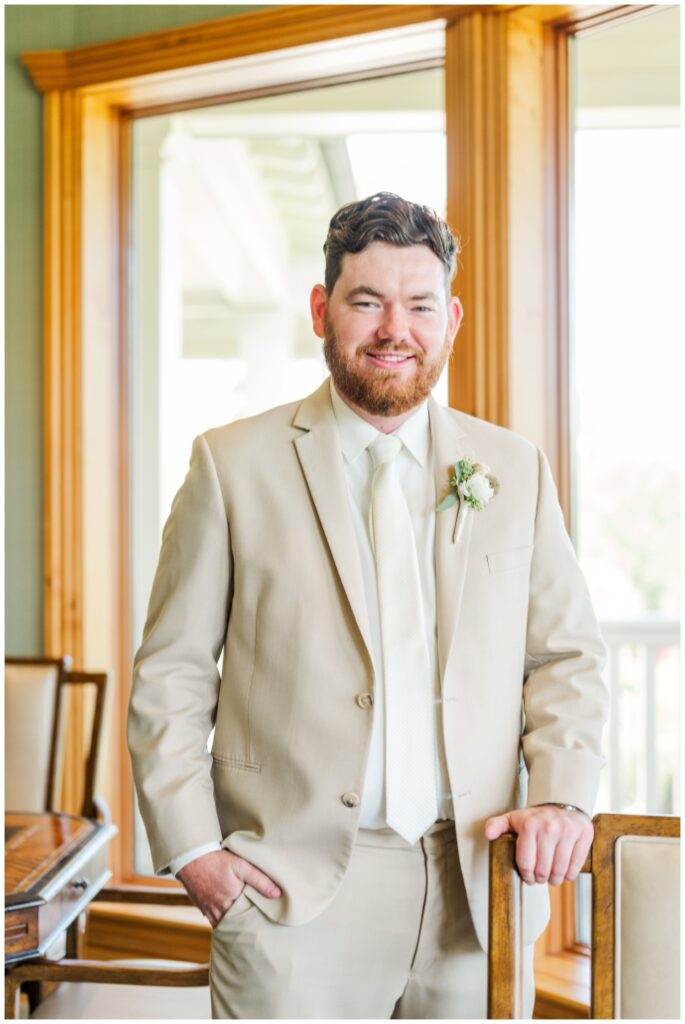 groom posing with his hand in his pocket wearing a beige linen suit for wedding