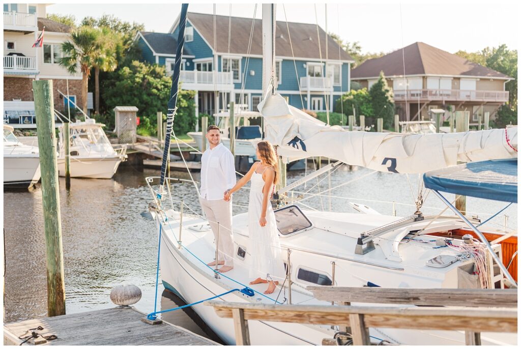 engagement couple posing on a sailboat in Carolina Beach