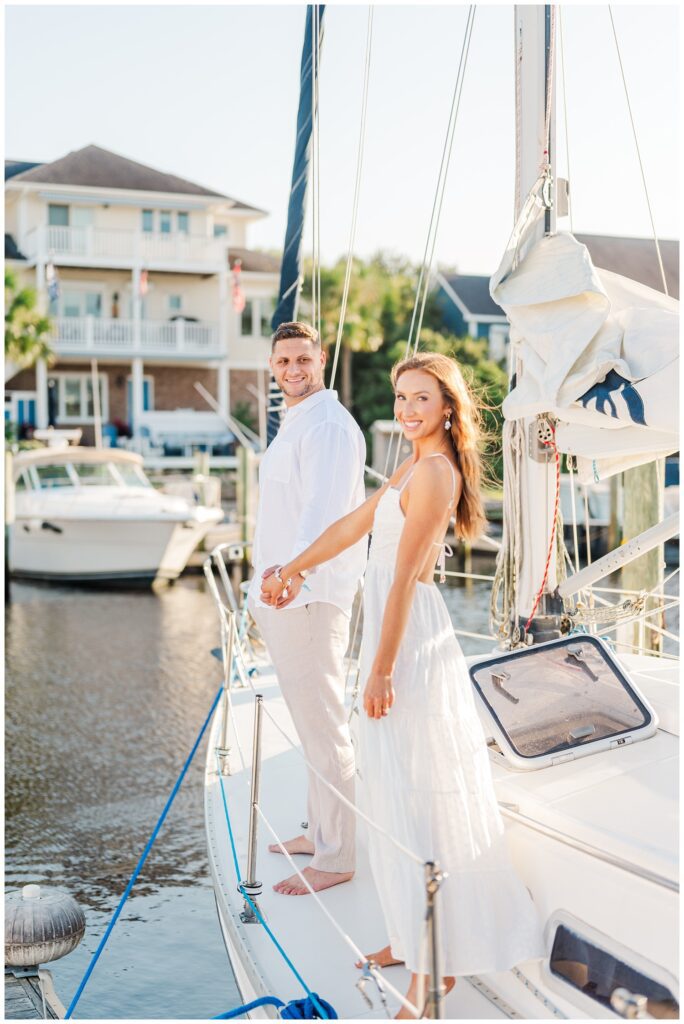 couple holding hands on a sailboat next to the dock