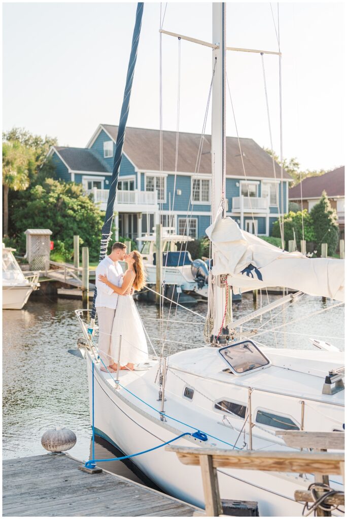 engaged couple sharing a kiss on  sailboat in Carolina Beach