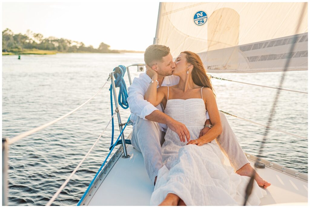 engaged couple kissing on a sailboat at golden hour in North Carolina