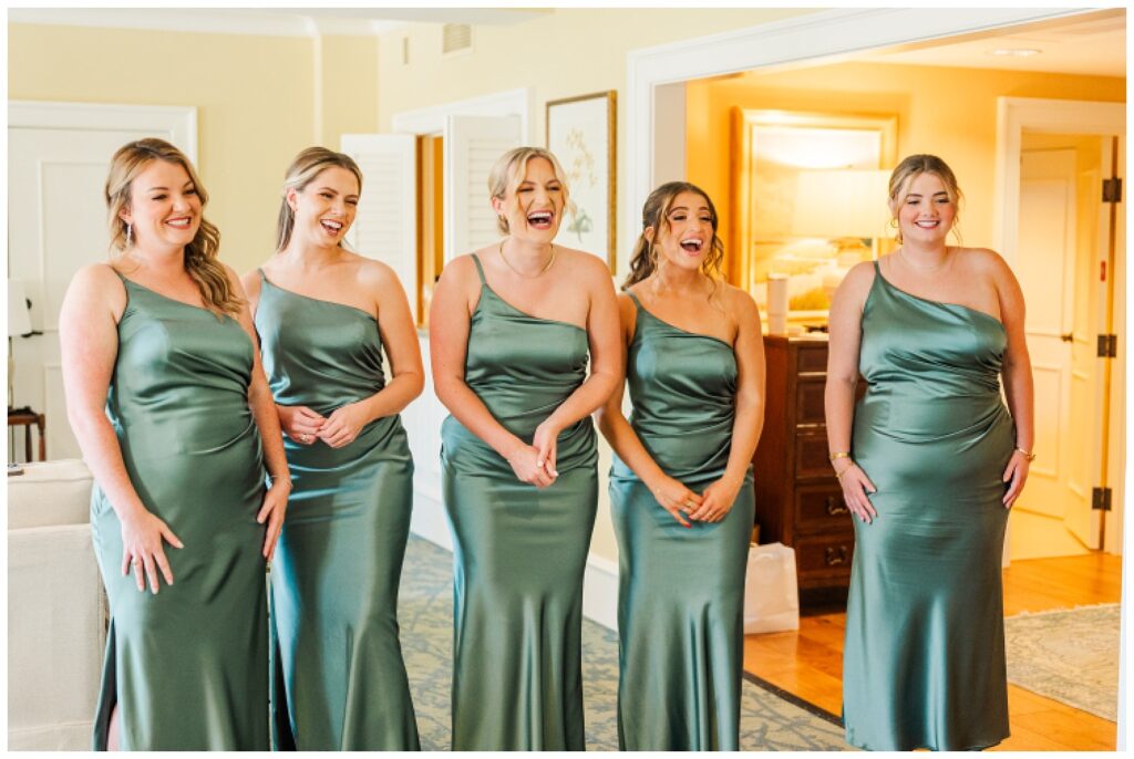 bridesmaids wearing dark sage green dresses surprised by the bride in her gown