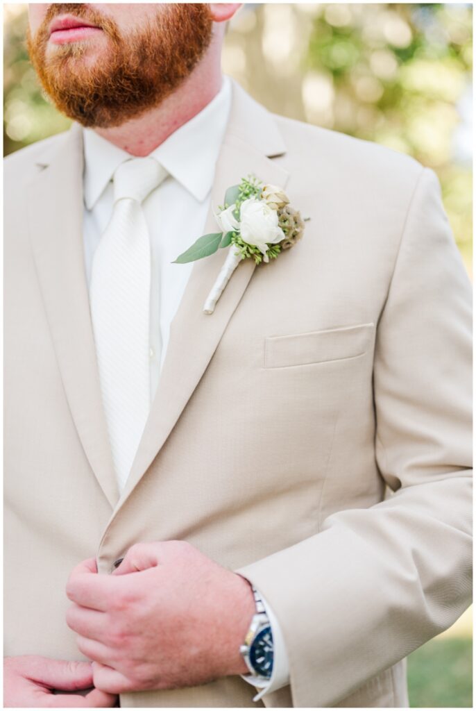 detail of the groom's green and white boutonniere and beige linen suit