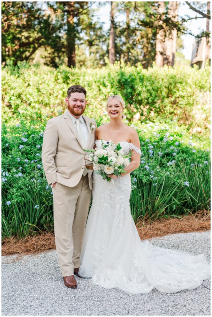 bride and groom posing on the sidewalk in front of purple flowers in Hilton Head