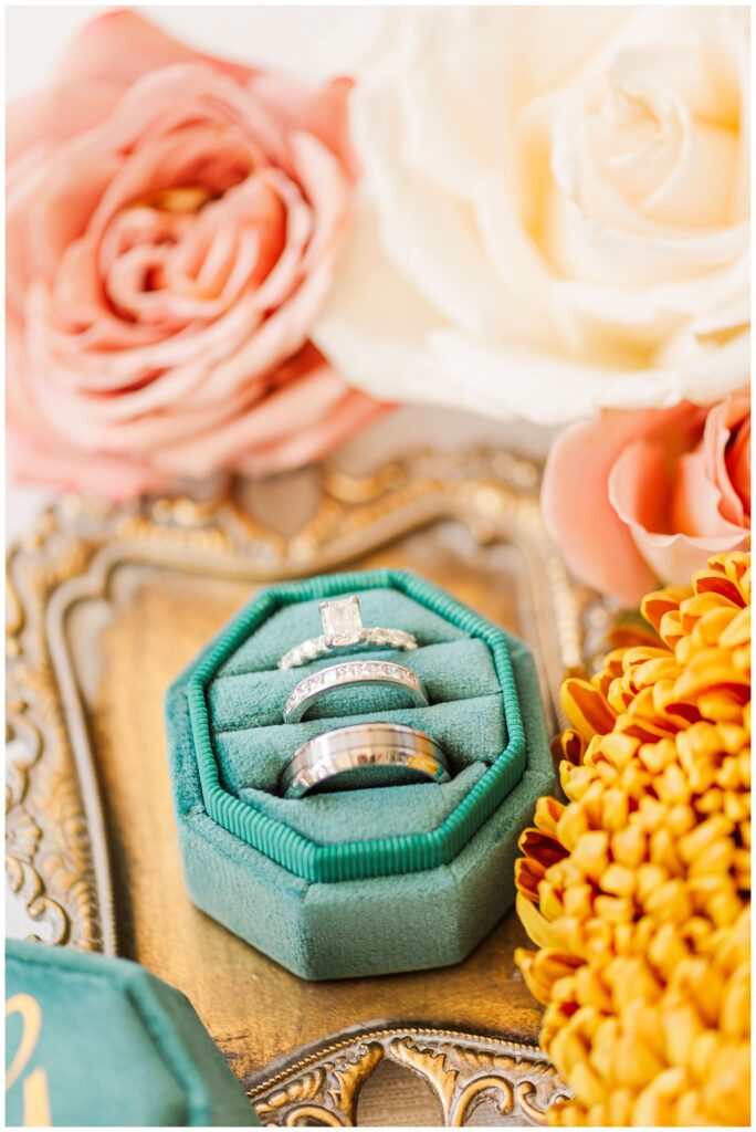 bride and groom's wedding rings sitting in a green box on top of metal tray