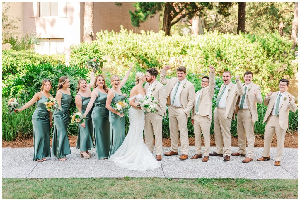 wedding party cheering on the bride and groom as they kiss 