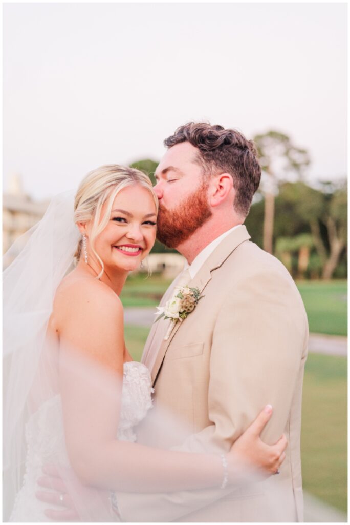 groom kisses bride during sunset on the golf course in Hilton Head