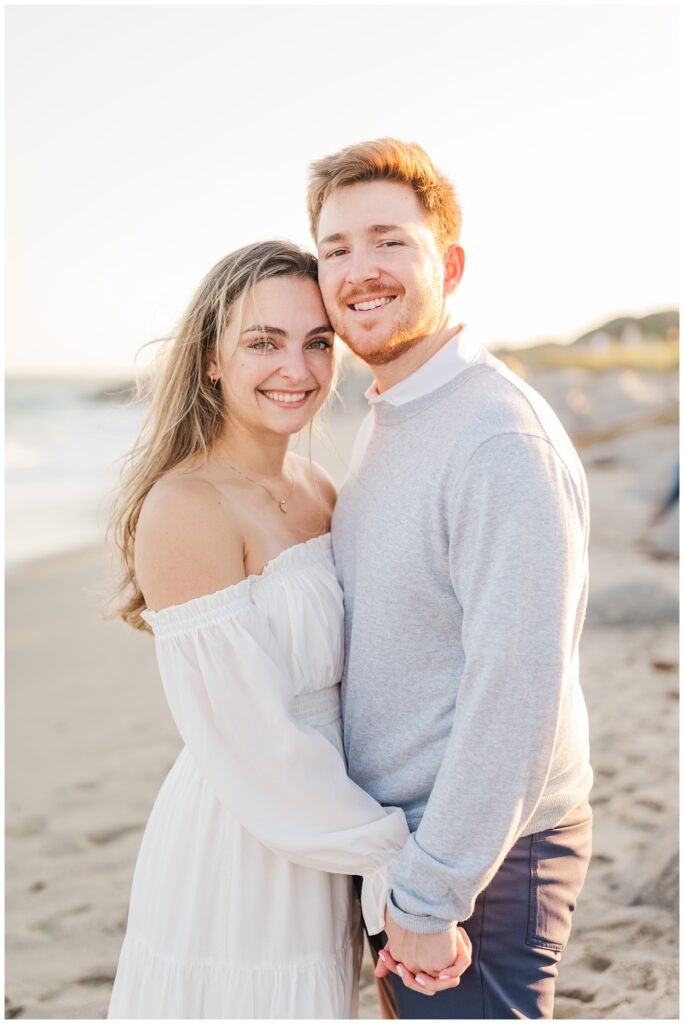 couple smiling and holding hands on Kure Beach during Fort Fisher engagement session