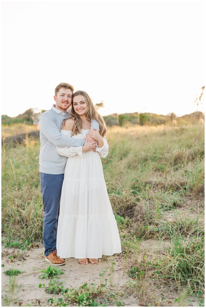 engaged couple posing among grass and sand at Fort Fisher, NC