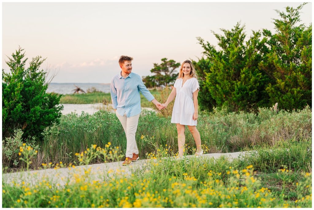 couple walking along the boat ramp at Fort Fisher near some yellow flowers