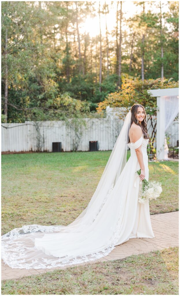 bride showing off her dress and veil wile posing on the sidewalk at wedding venue