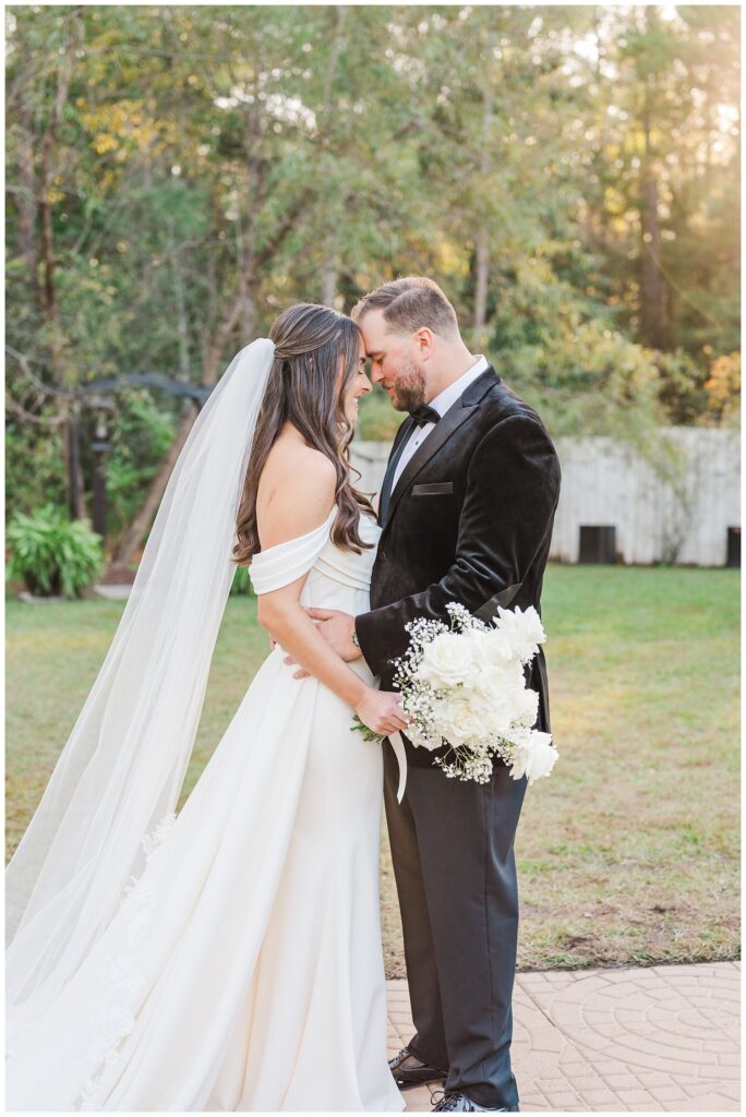 groom holding his hands around the bride's waist and she holds her bouquet