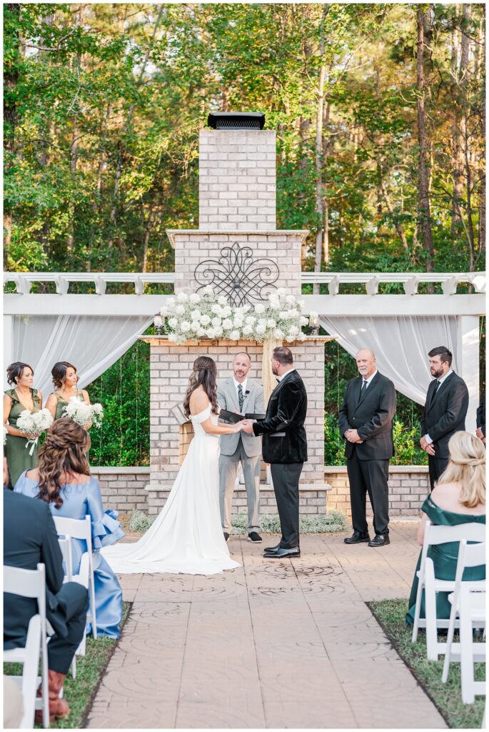 pastor speaking to the bride and groom while they hold hands during the ceremony