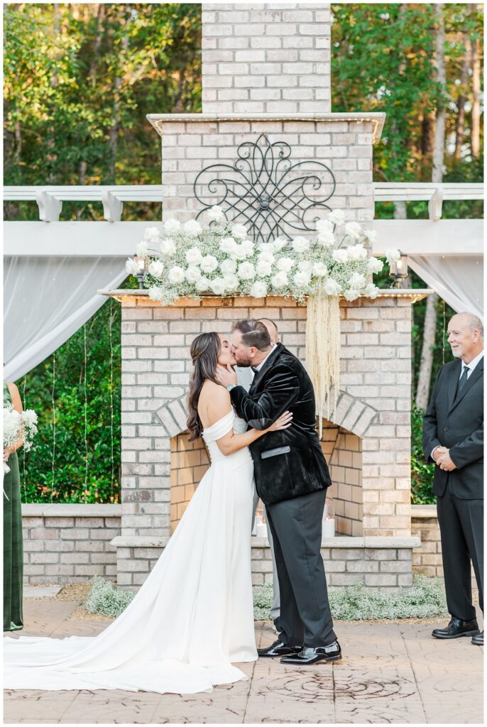 bride and groom kissing in front of an outdoor fireplace at Malachi Meadows venue