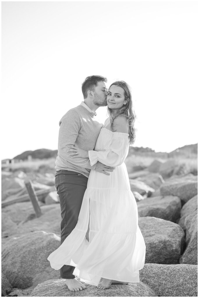 couple posing barefoot on the large rocks at Fort Fisher for engagement portraits 