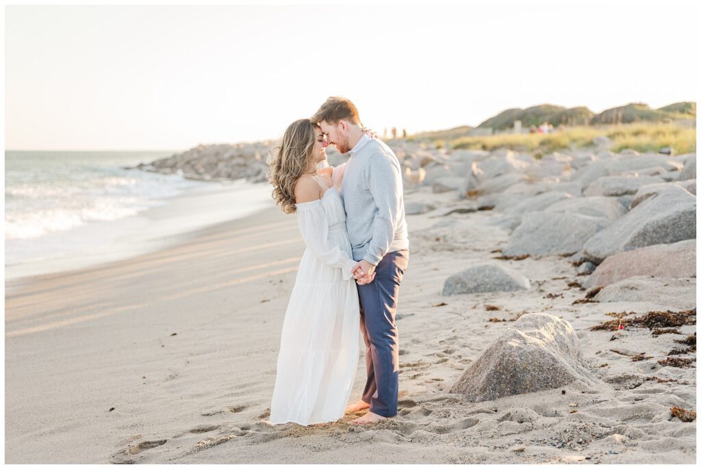 couple posing barefoot on the beach next to the large rocks at Fort Fisher 