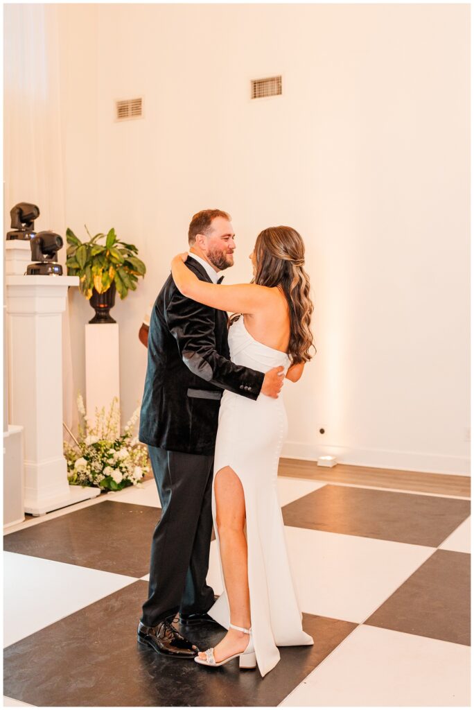 bride and groom have first dance on a black and white floor at wedding reception 