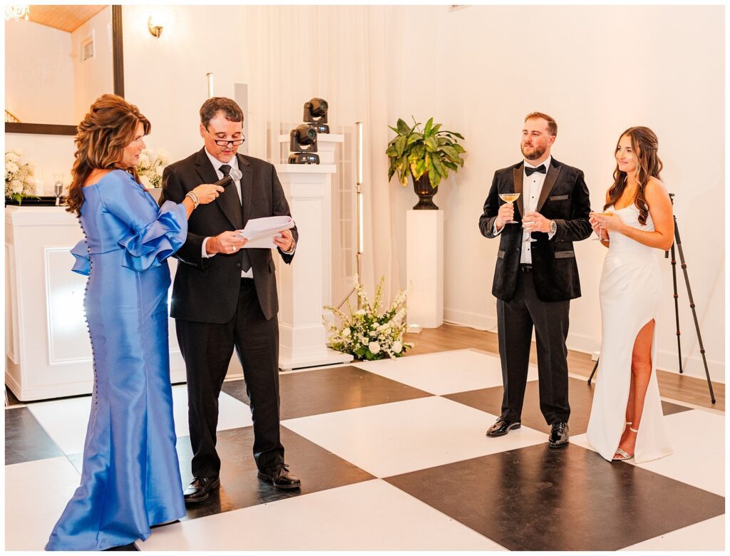 bride's parents giving a speech while the wedding couple looks on with champagne 