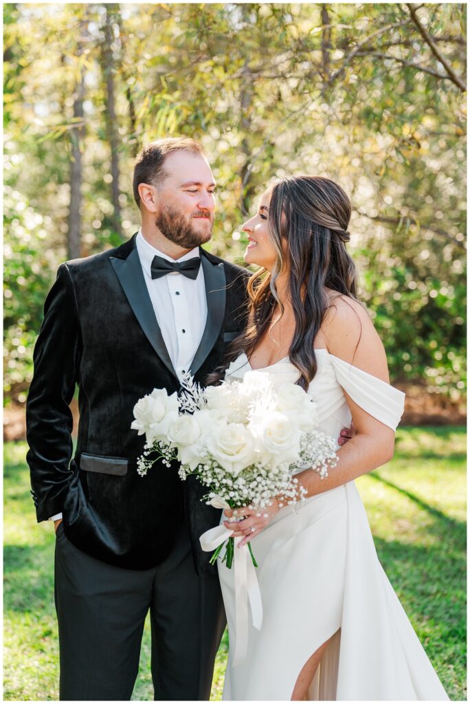 wedding couple smiling at each other in front of some trees at Currie, NC venue