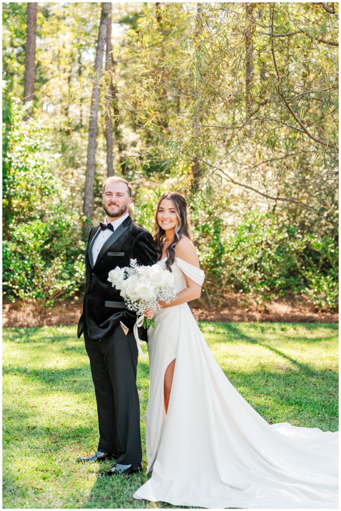 bride standing behind the groom holding her bouquet on the grass in NC