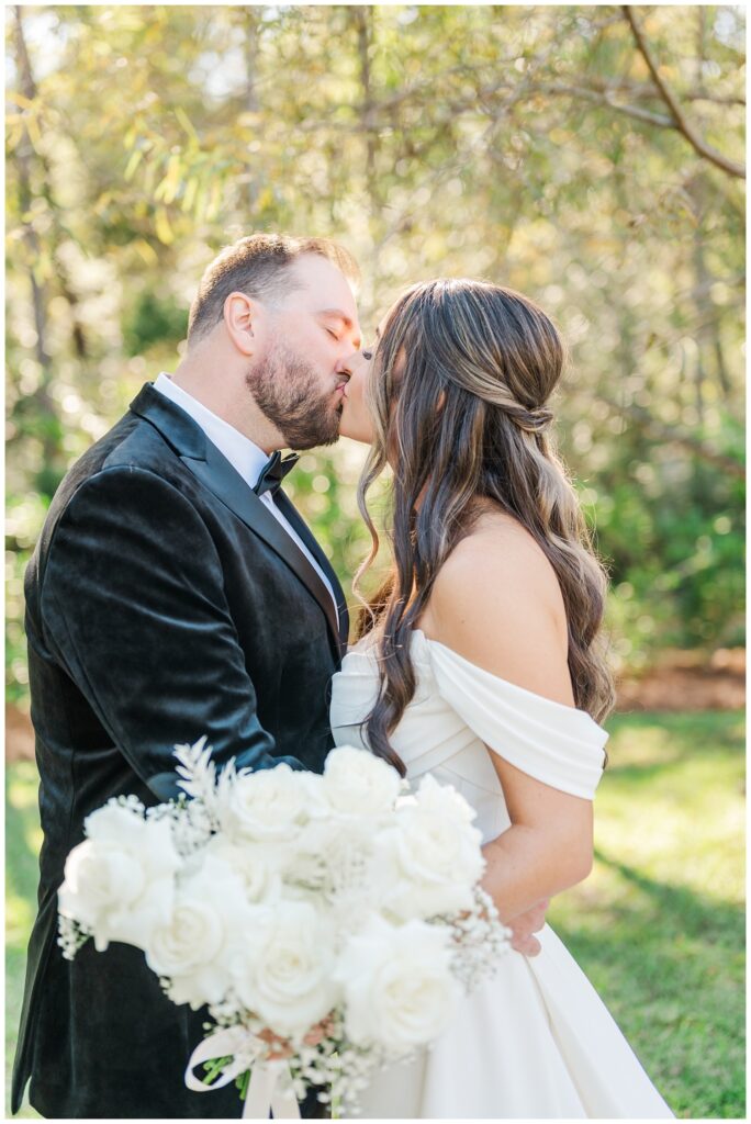 bride and groom share a kiss while posing in the grass at NC wedding venue