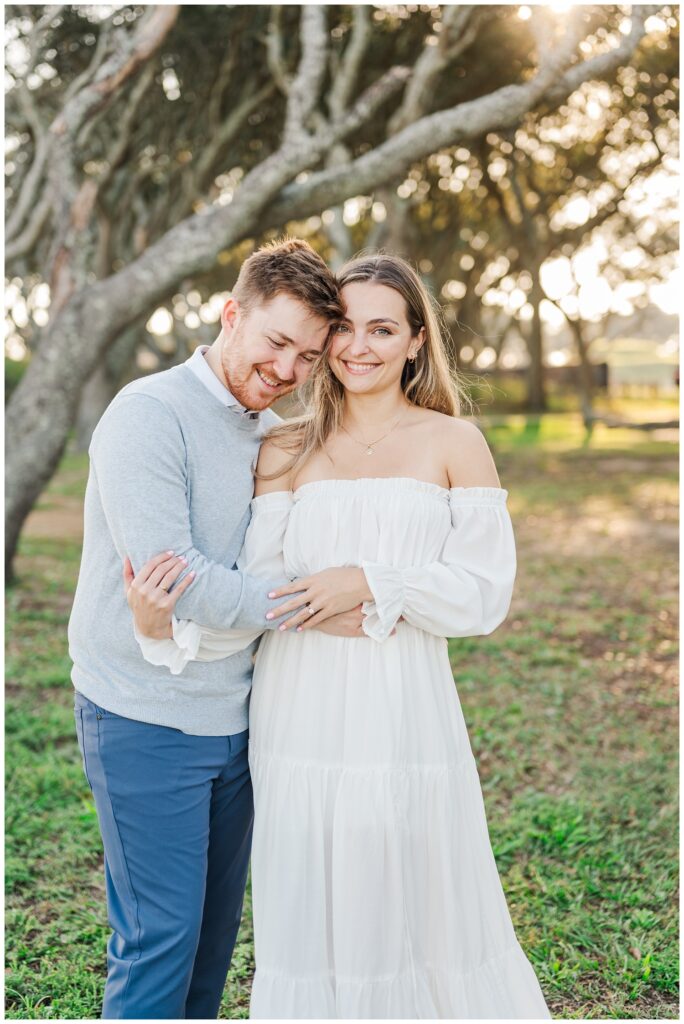 couple smiling and posing at golden hour for engagement portraits at Fort Fisher