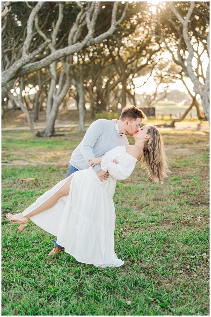 man dipping back his fiancee for a kiss at Fort Fisher, NC