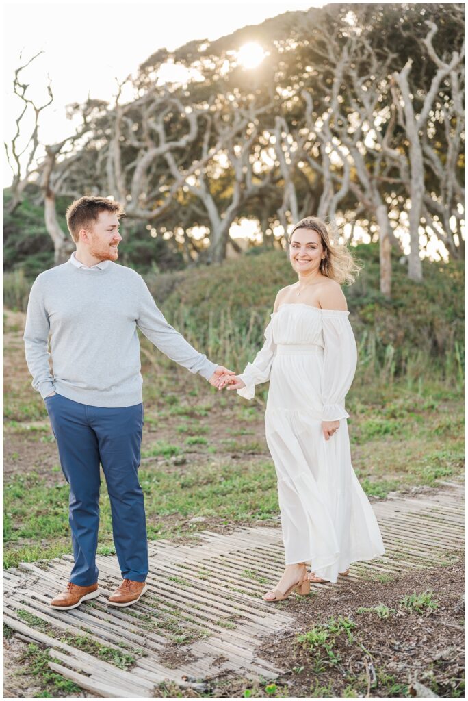 engaged couple walking together down a beach path holding hands at Fort Fisher