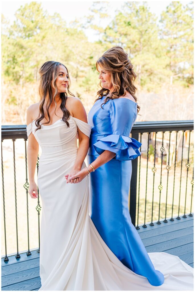 bride's mom smiling at her after zipping up her dress on the balcony outside 