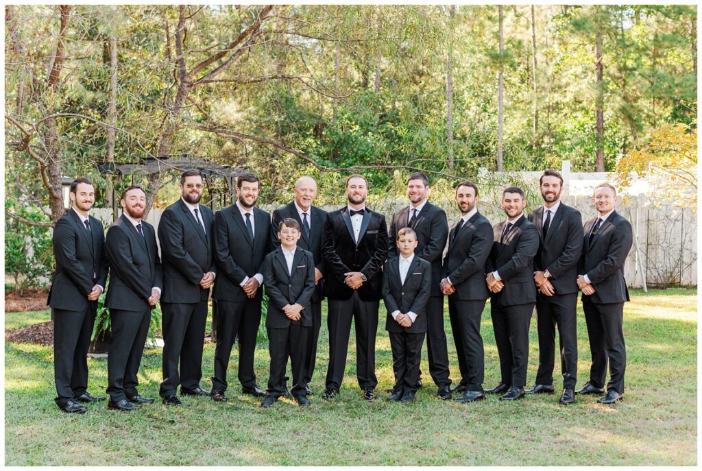 groomsmen posing in a straight line on the grass at Malachi Meadows wedding