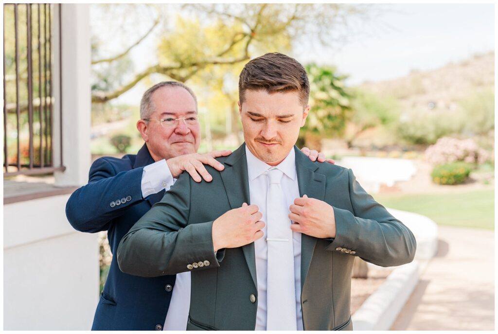 groom's dad helping the groom adjust his jacket outside before the ceremony in AZ