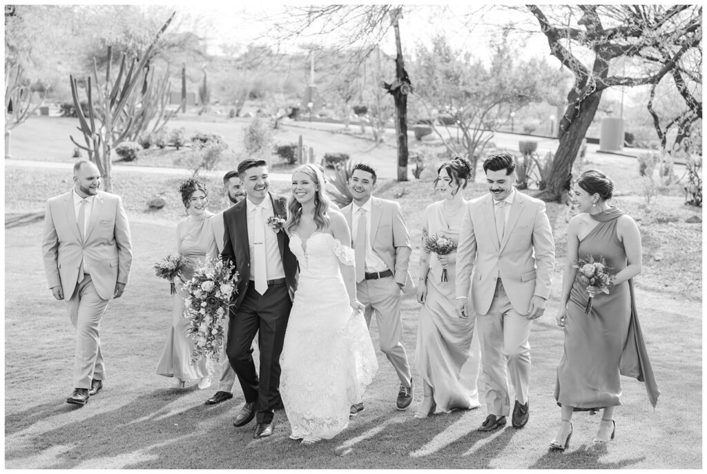 wedding couple walking and laughing with bridal party behind them at Arizona venue