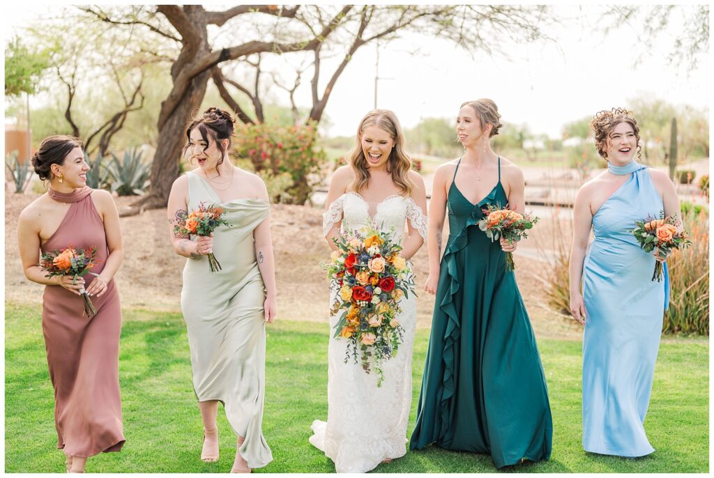 bride walking and laughing with her bridesmaids on the lawn at Arizona wedding venue