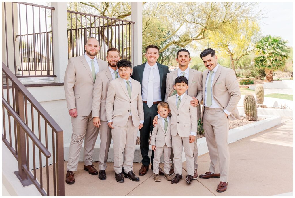groomsmen and ring bearer posing for portraits next to the porch outside