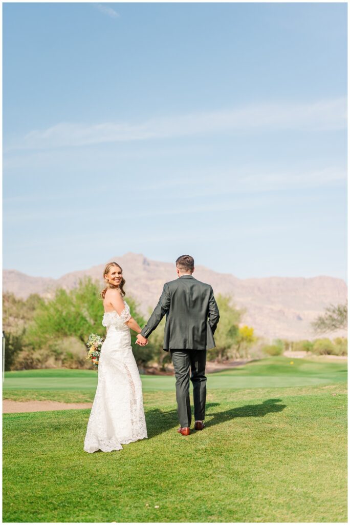 bride and groom holding hands walking away on the golf course in Arizona