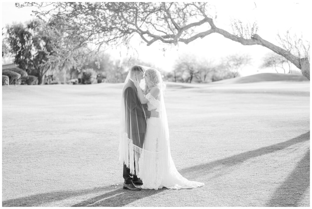 wedding couple under the bride's veil in front of a large tree in Arizona