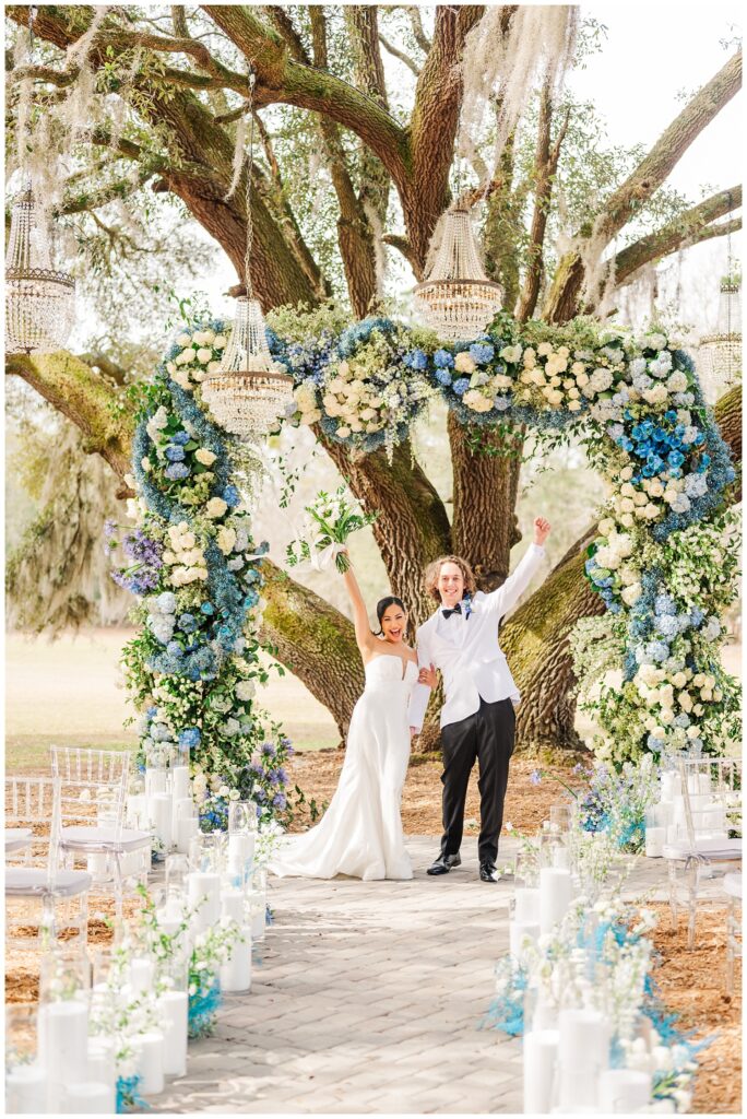 wedding couple cheering in front of a live oak tree at Hewitt Oaks venue