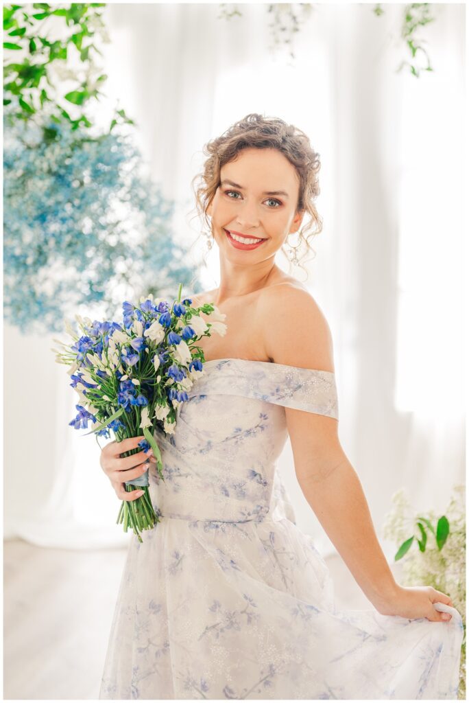 bride wearing a blue and white off shoulder wedding dress while holding a small bouquet