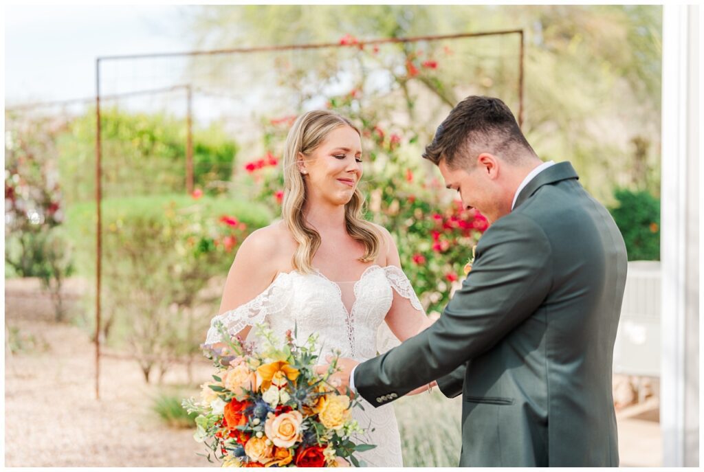 bride crying while the groom looks at her dress during first look