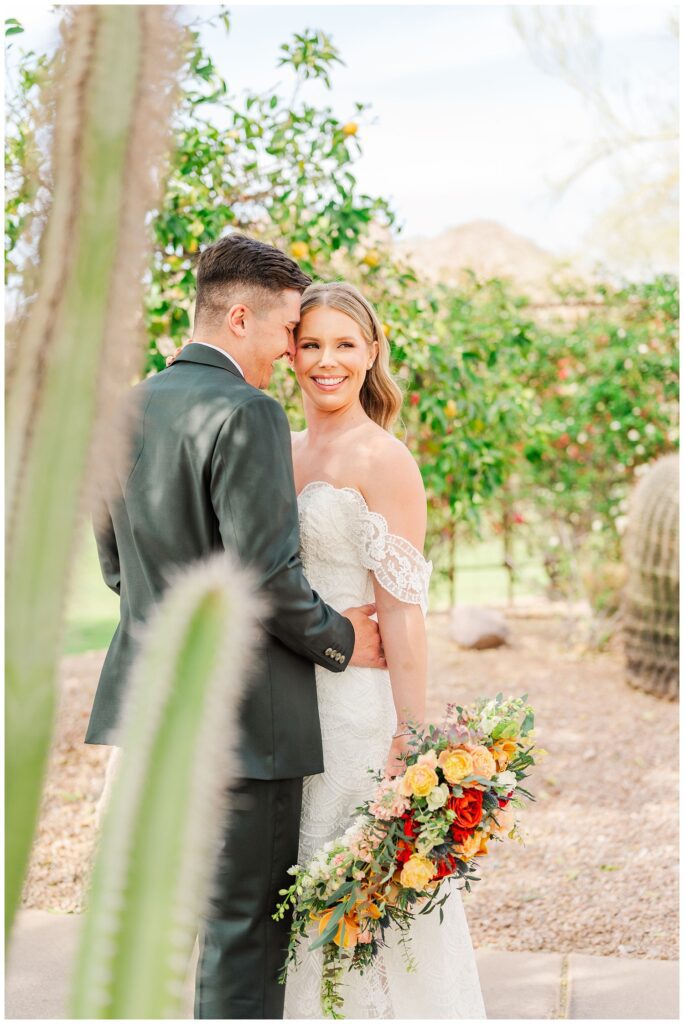 bride and groom posing togetherr next to some cacti at AZ wedding venue