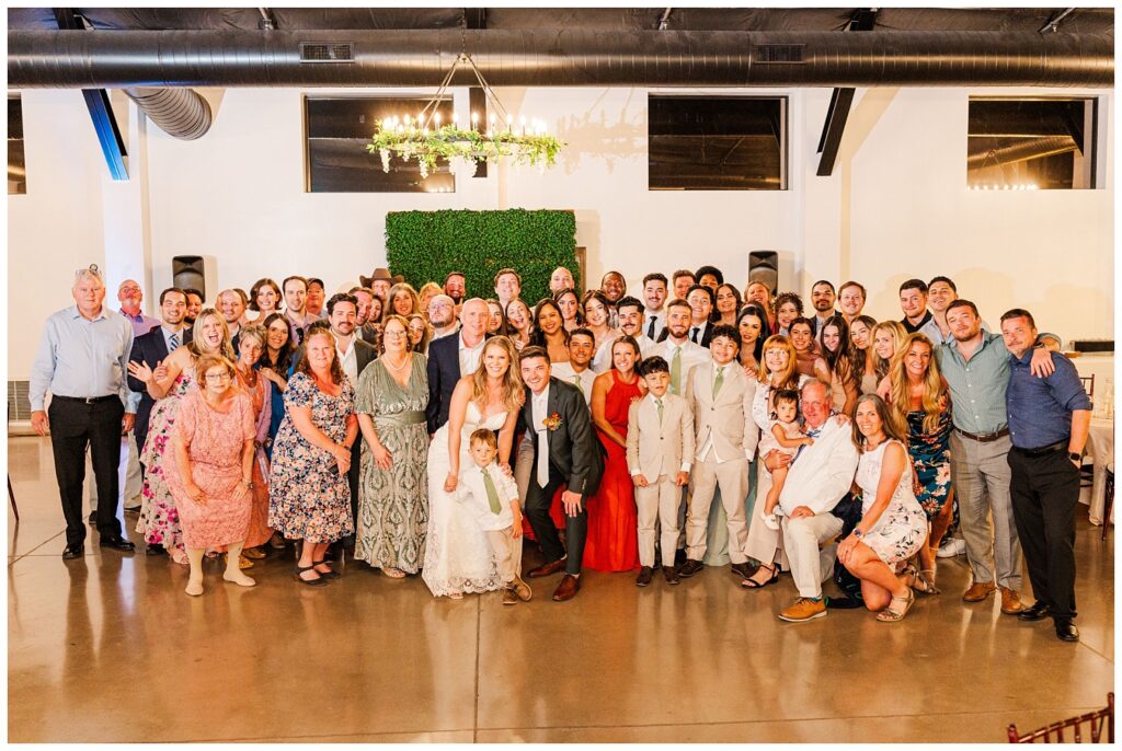 large group picture of bride and groom and wedding guests at reception